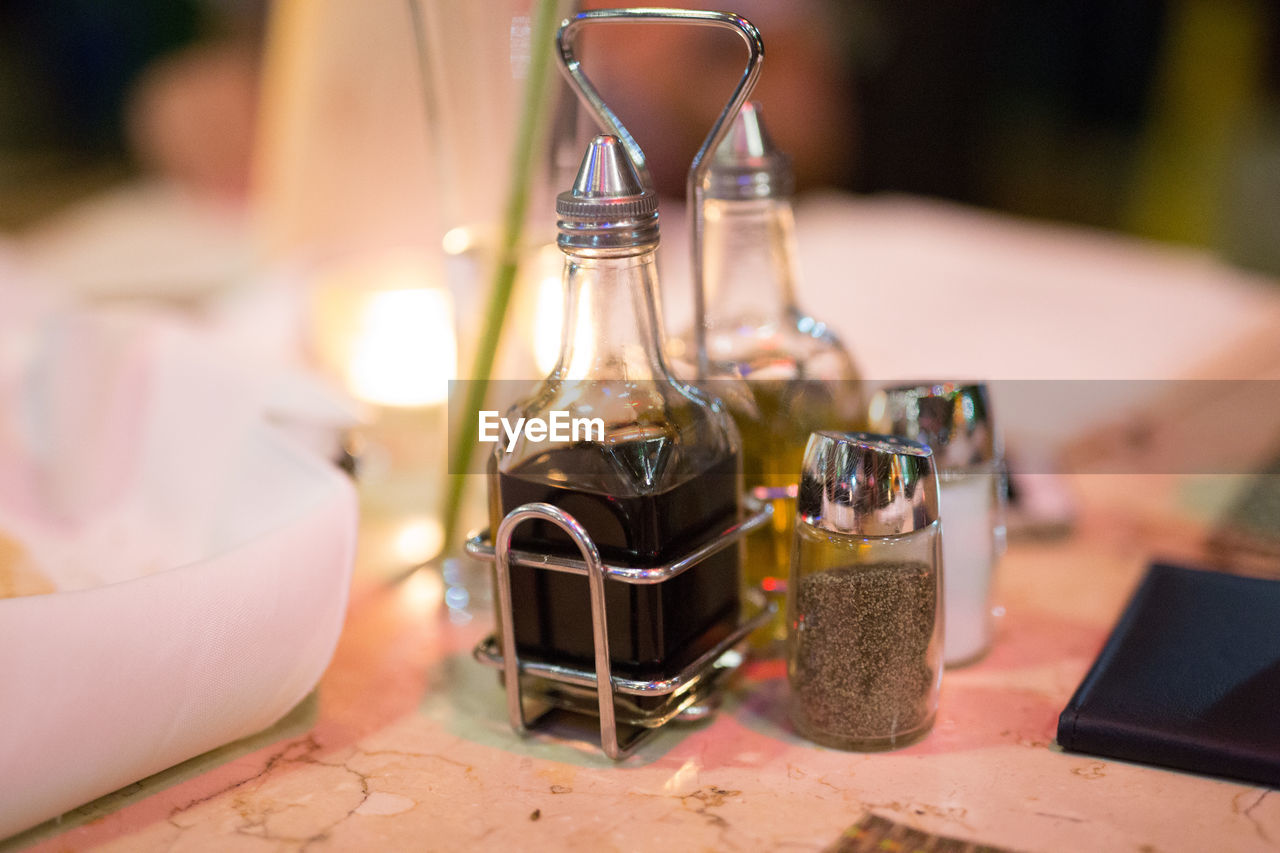 Close-up of balsamic vinegar with olive oil by salt and pepper on table