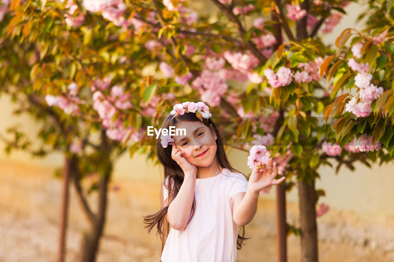 Portrait of smiling girl standing against flowering tree