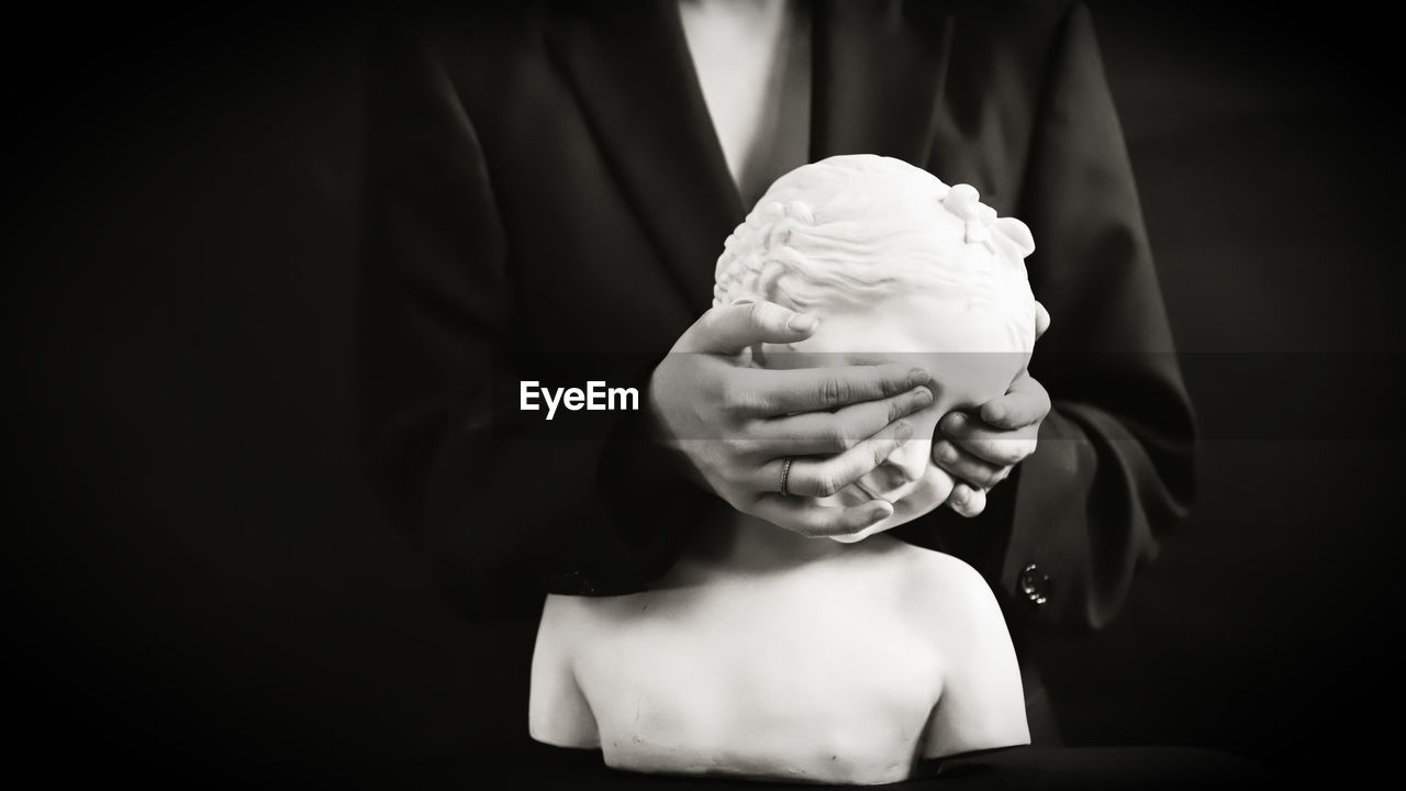 WOMAN HOLDING ICE CREAM CONE AGAINST BLACK BACKGROUND