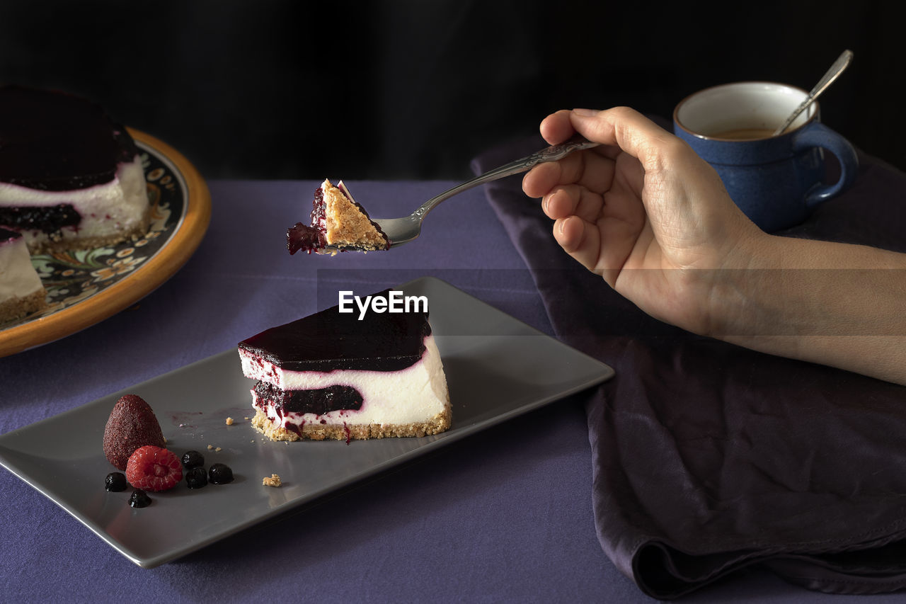 A bite of berries cheesecake supported by female hand. 