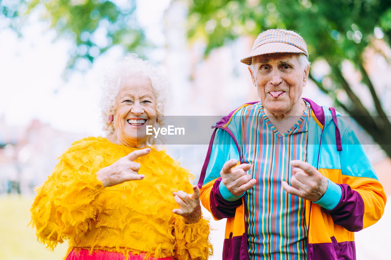 portrait of smiling friends standing against tree