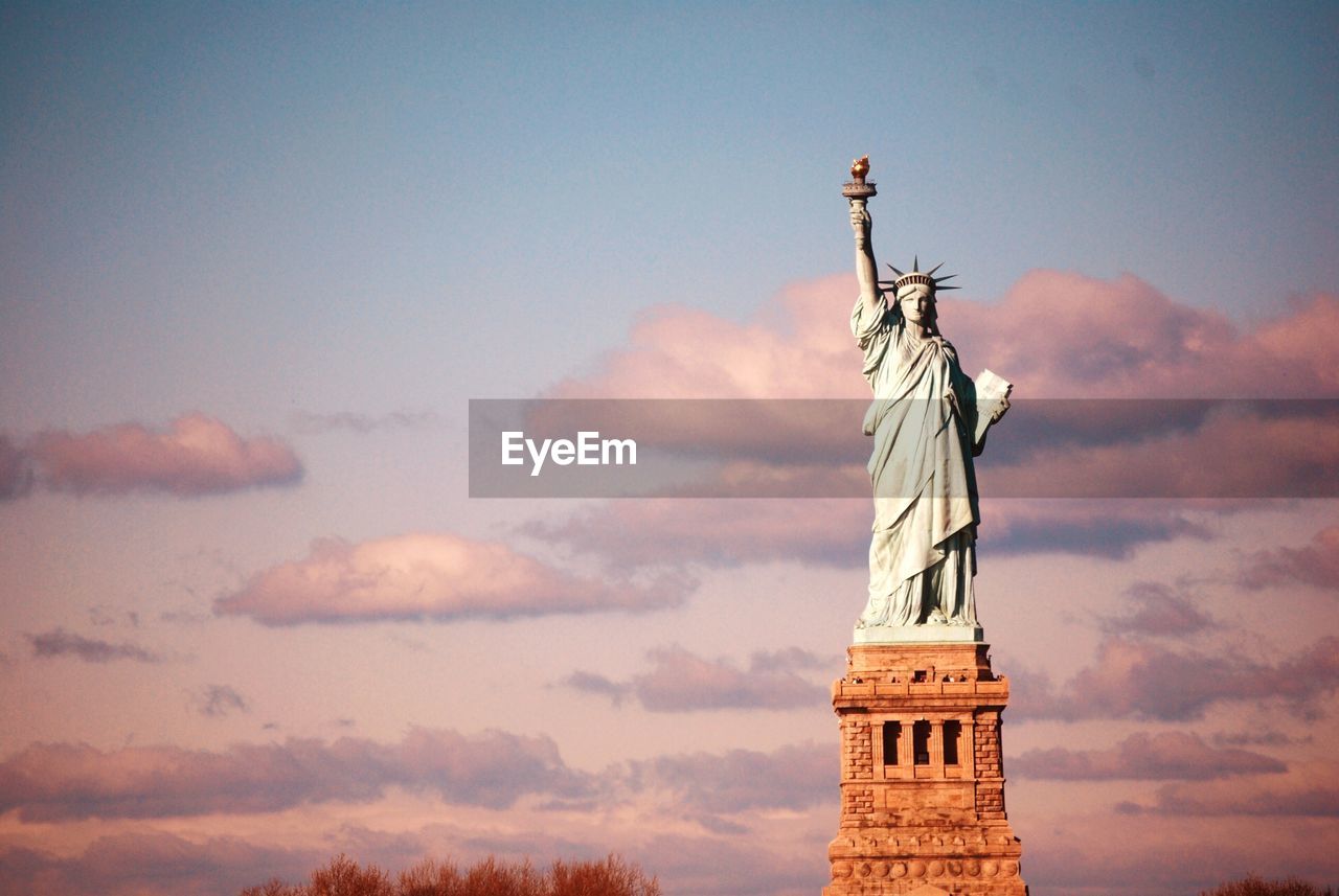 Low angle view of statue of liberty against cloudy sky