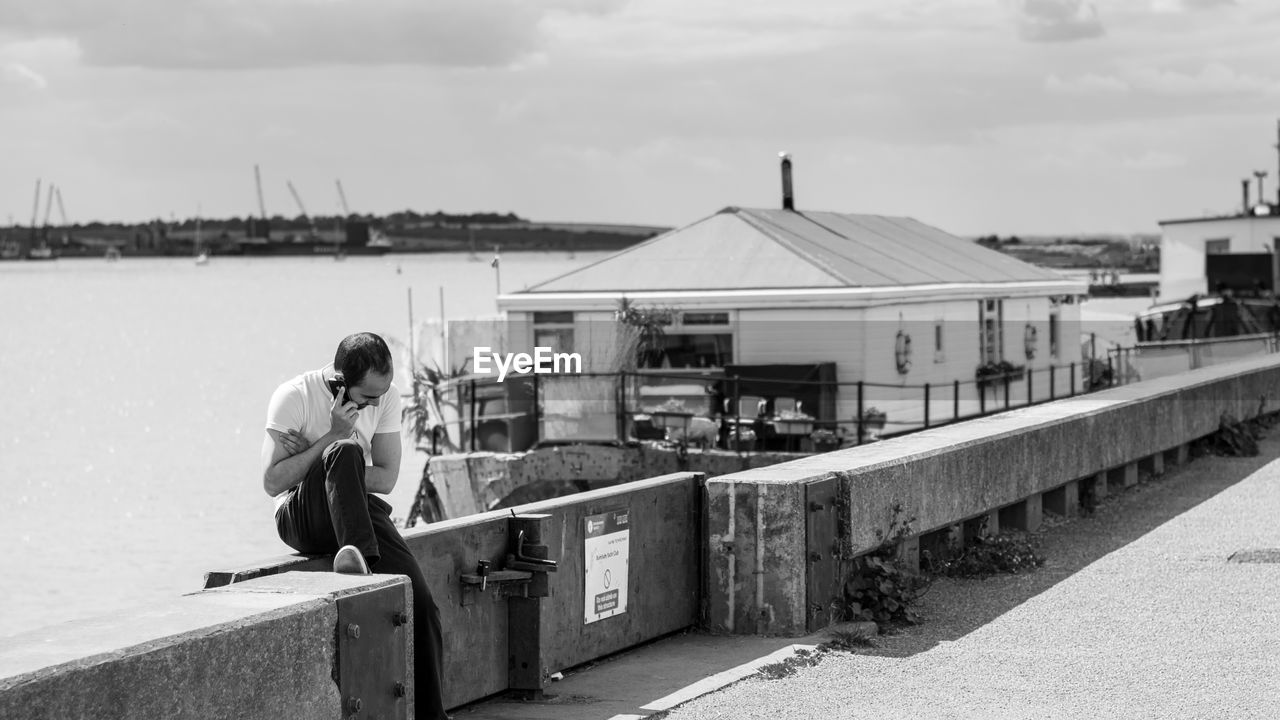 REAR VIEW OF BOY SITTING ON RAILING