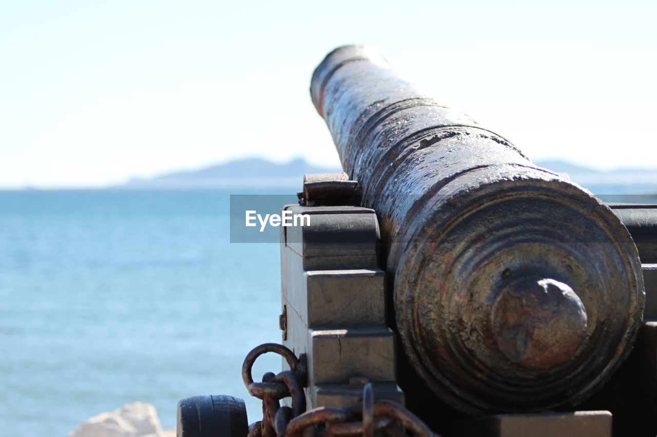 Close-up of old cannon at observation point by sea against sky