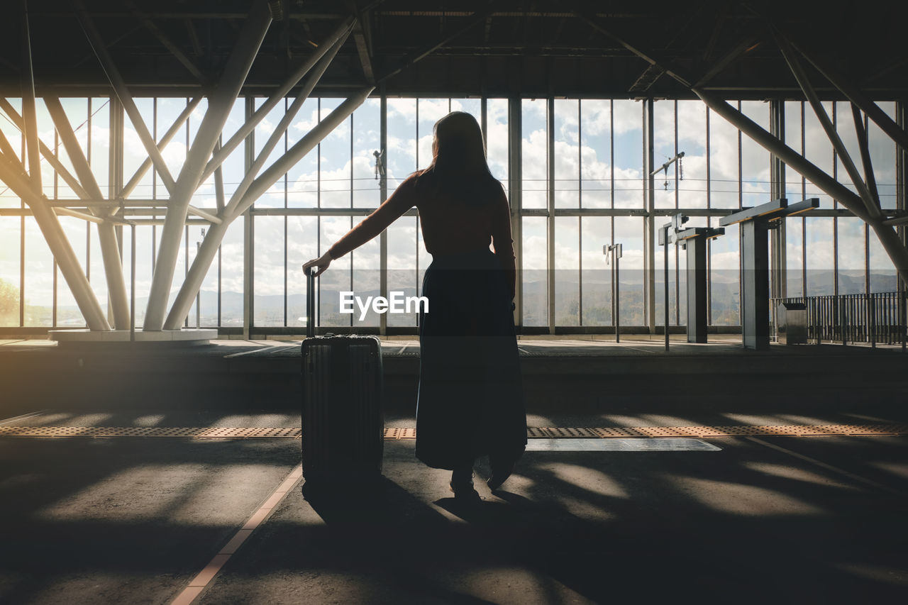 Woman with luggage standing at airport departure area