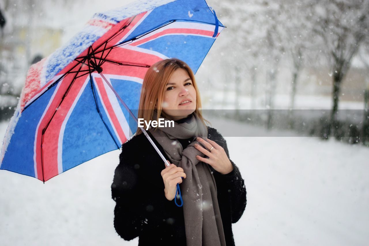 Portrait of woman with umbrella standing in snow