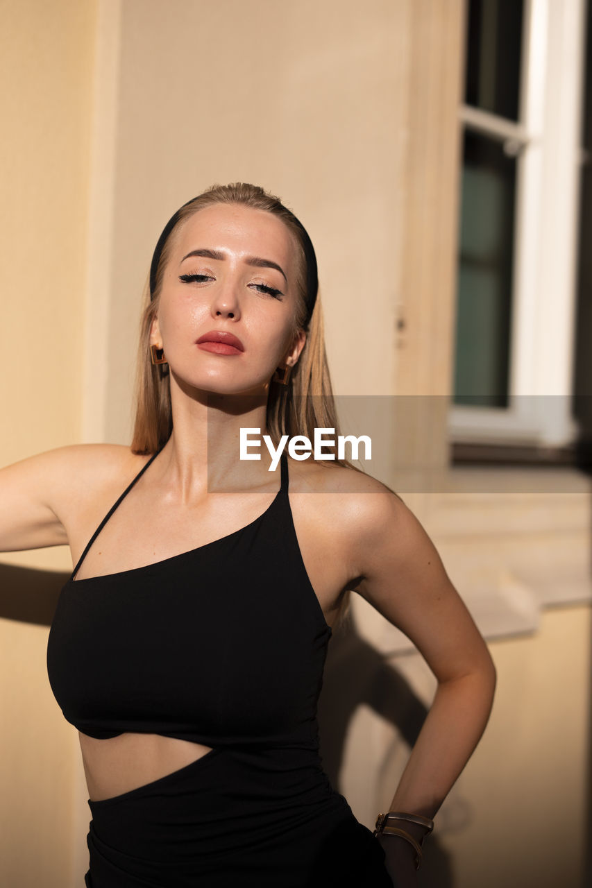 Portrait of young woman standing against wall