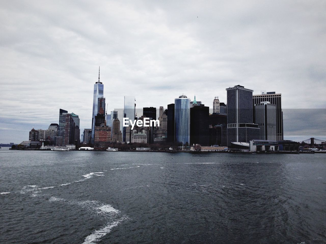 Urban skyline by east river against cloudy sky