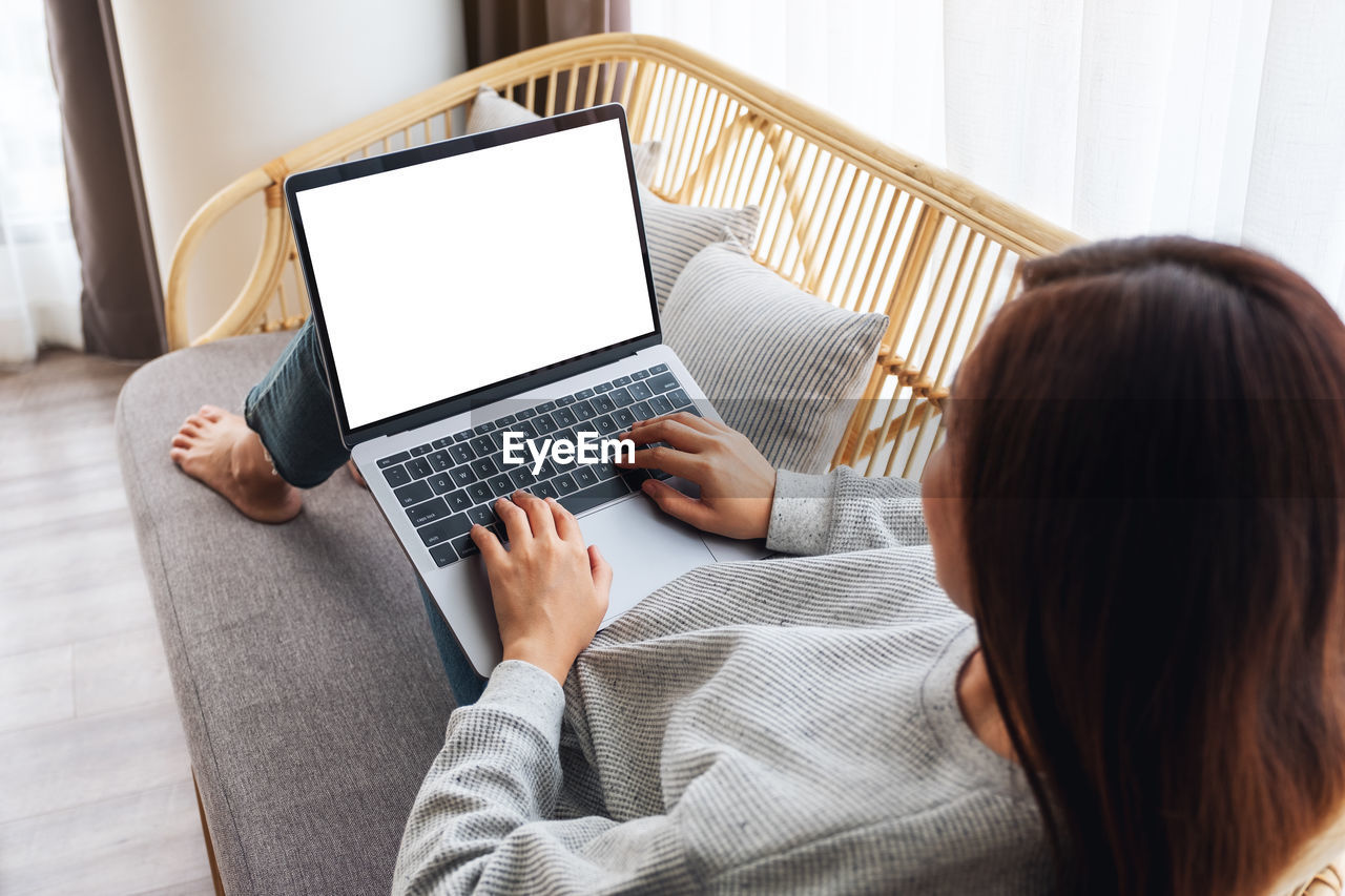 midsection of woman using laptop while sitting at home