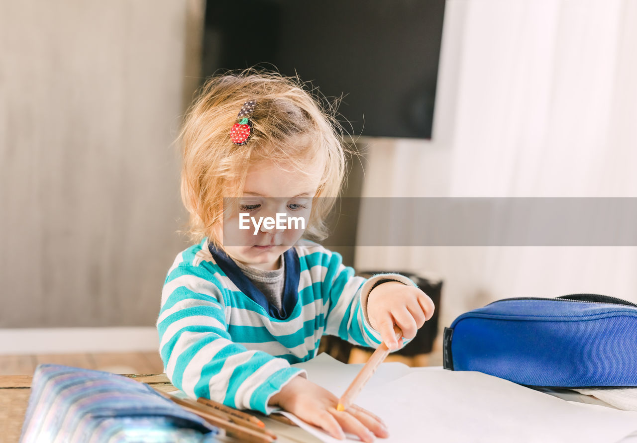 Girl holding pencil at home