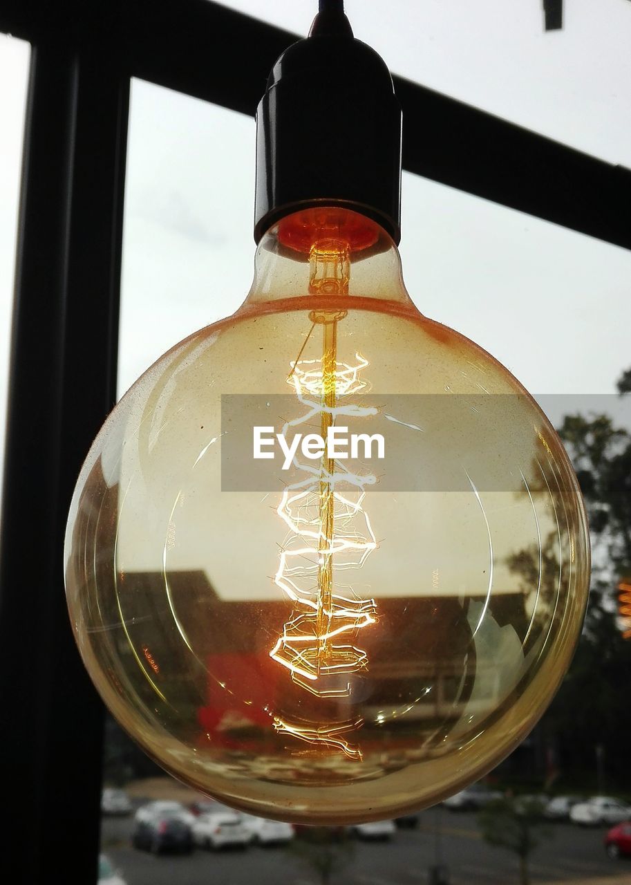 CLOSE-UP OF ILLUMINATED LIGHT BULB HANGING IN GLASS