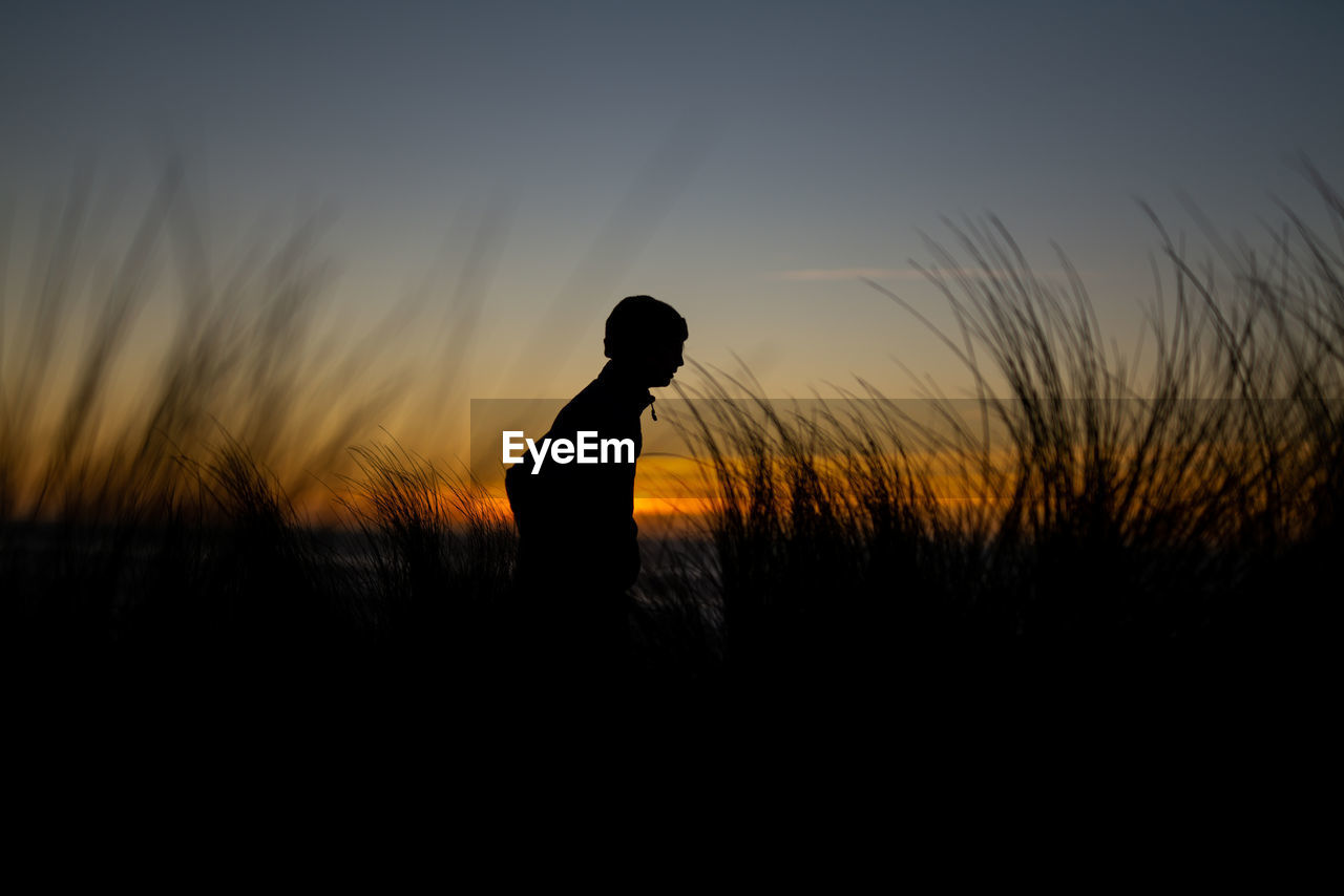 Silhouette of teen hiking along northern california dunes at sunset