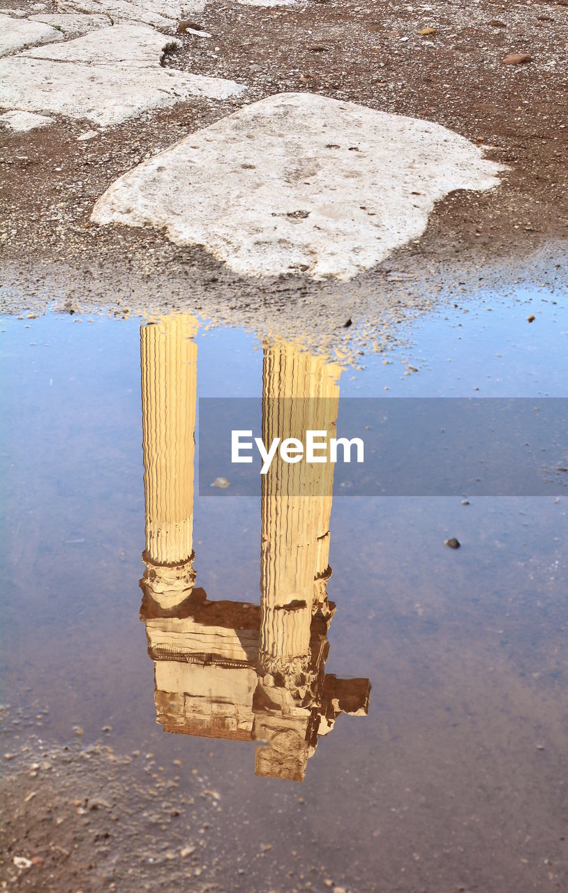 REFLECTION OF OLD BUILDING IN PUDDLE ON WATER