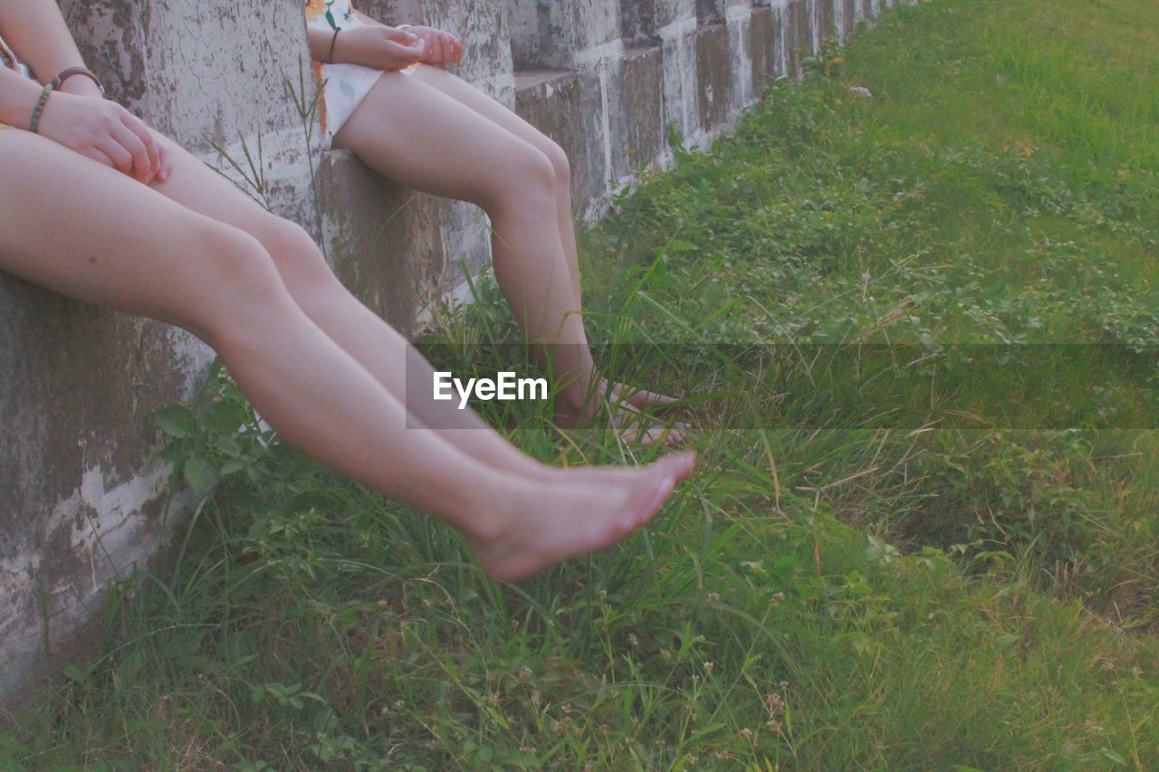 Low section of women sitting on retaining wall