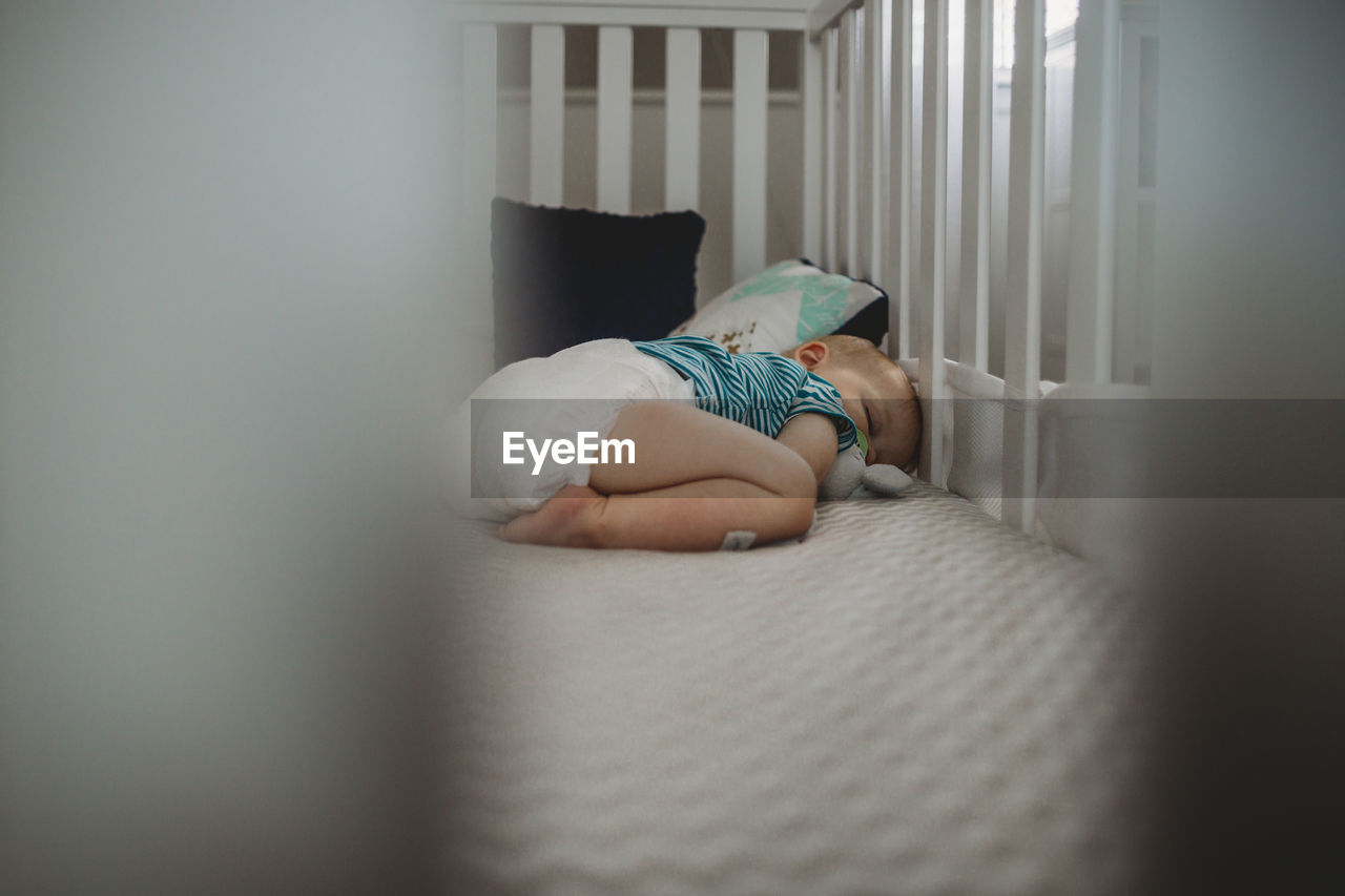 Baby boy sleeping in crib at home