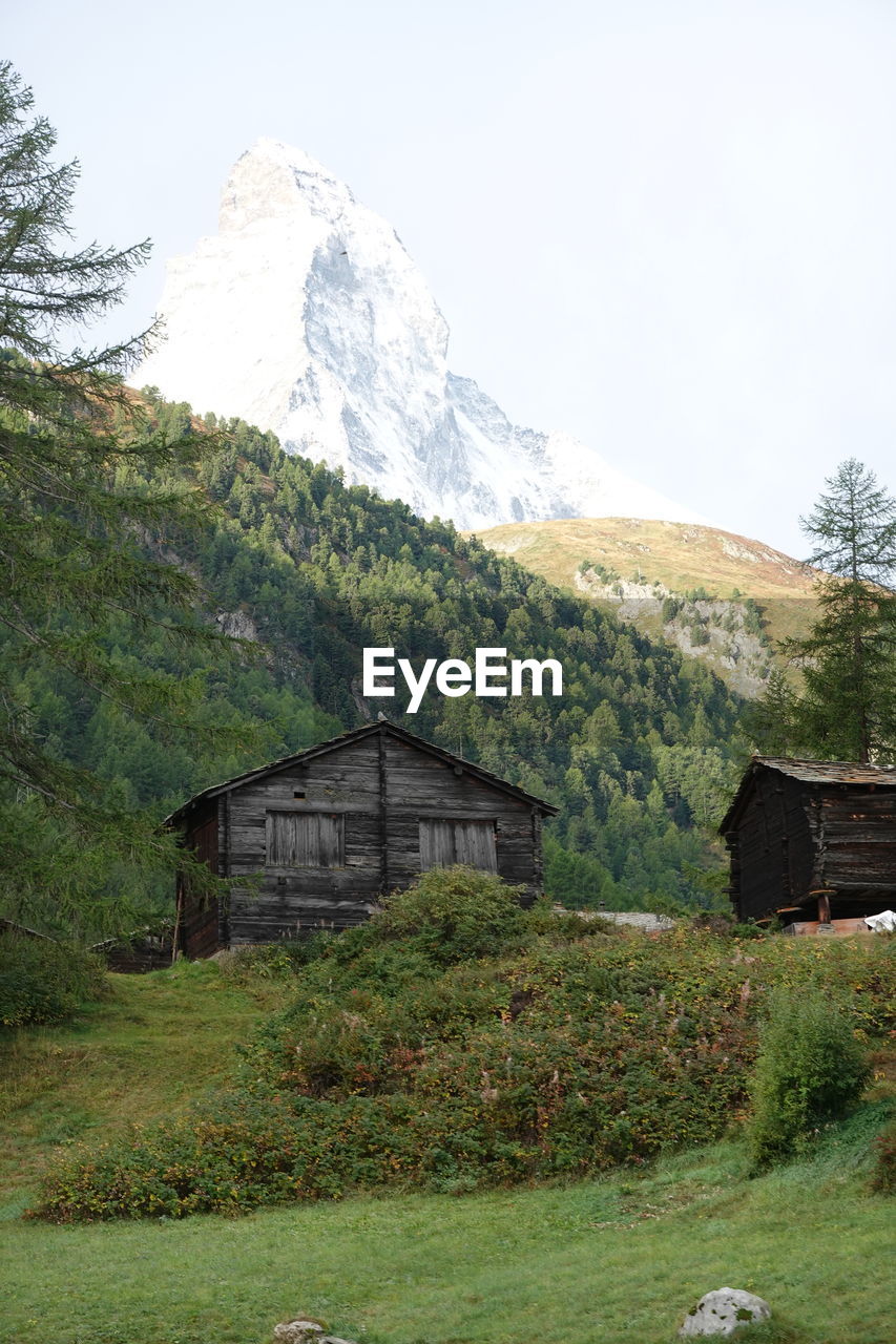 BUILT STRUCTURE ON FIELD BY MOUNTAIN AGAINST SKY