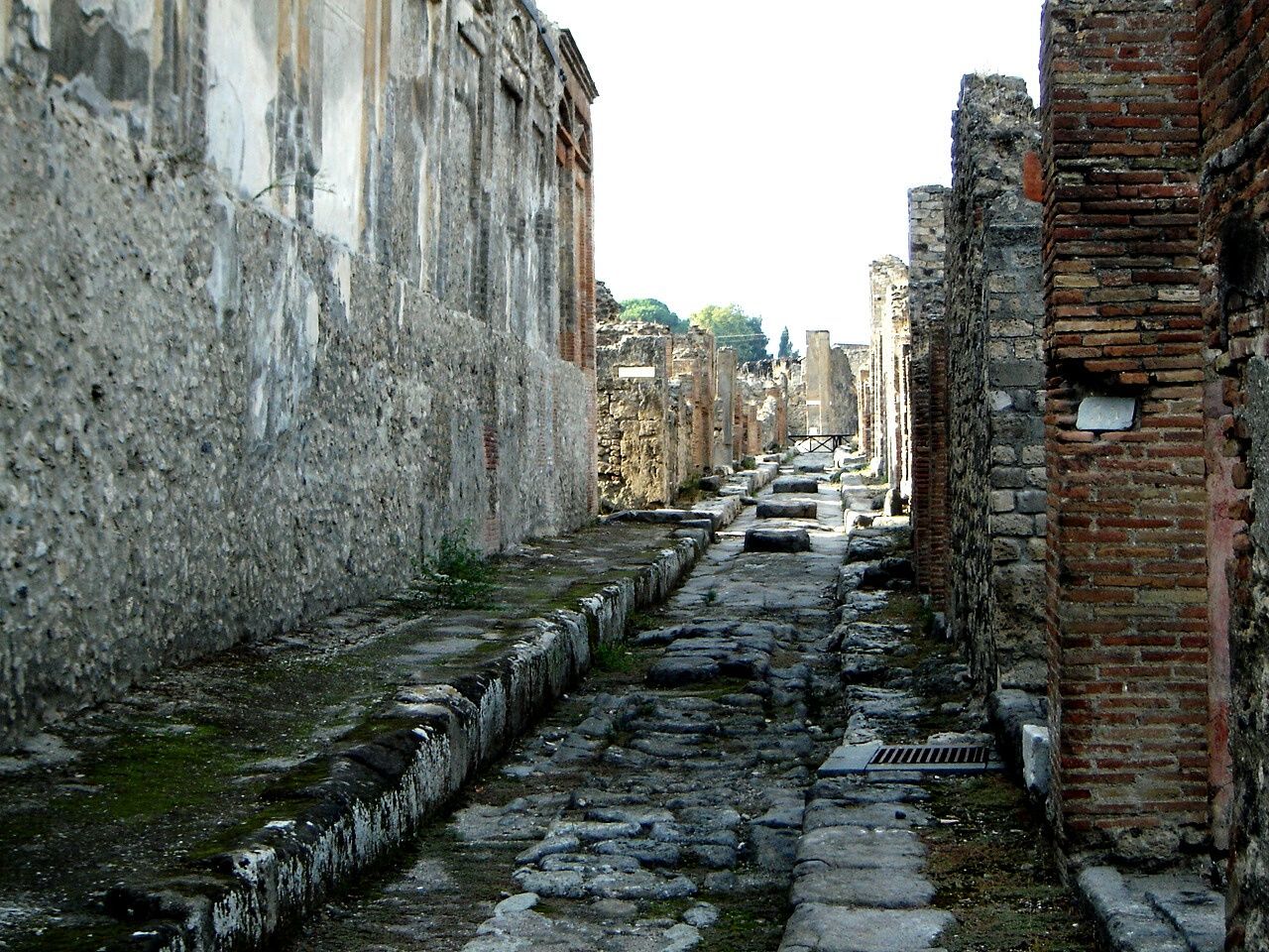 WALKWAY AMIDST BUILDINGS IN CITY AGAINST SKY