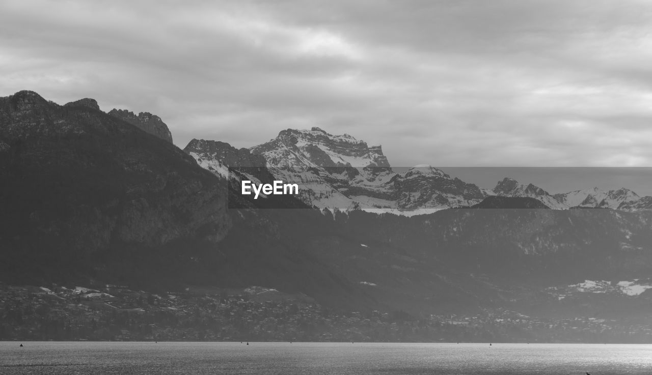 Scenic view of mountains and sea against cloudy sky