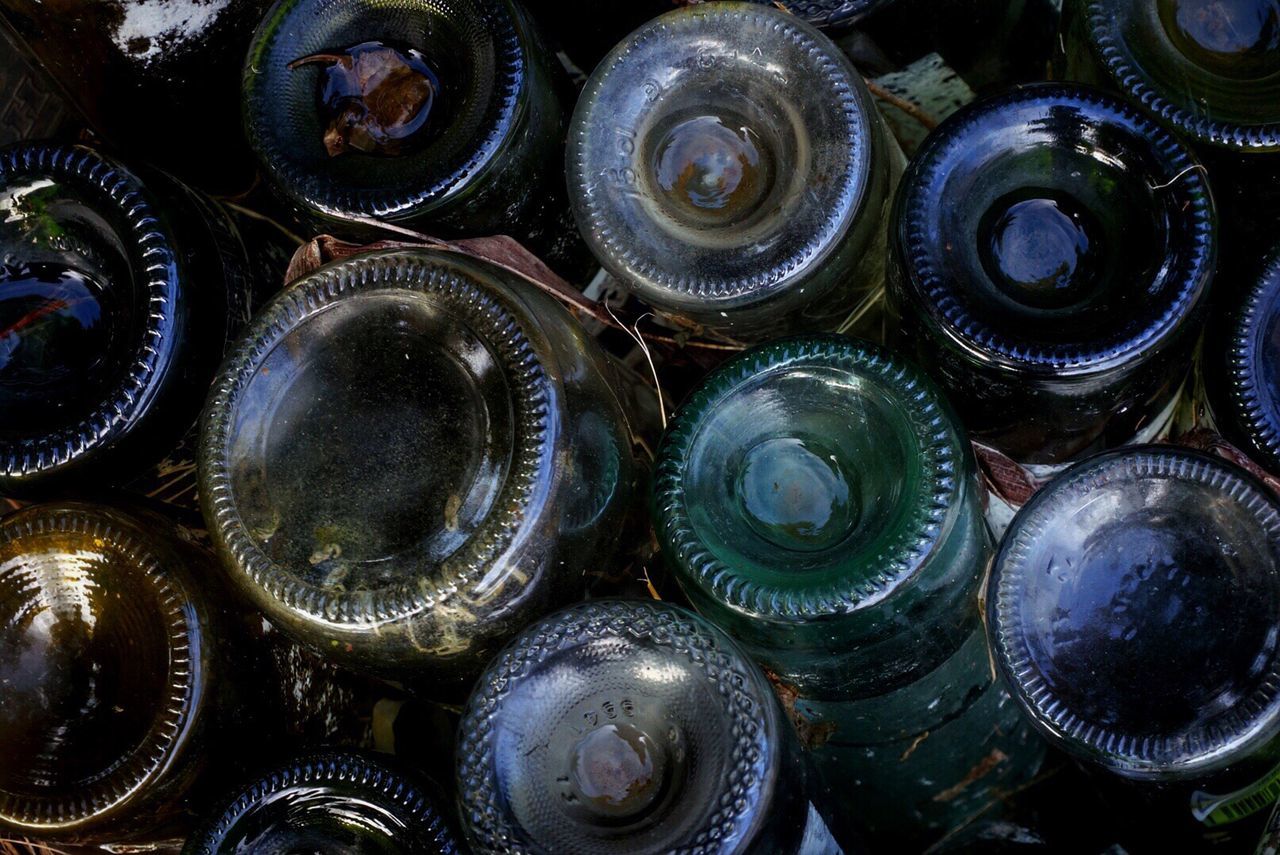 Full frame shot of upside down wet glass bottles