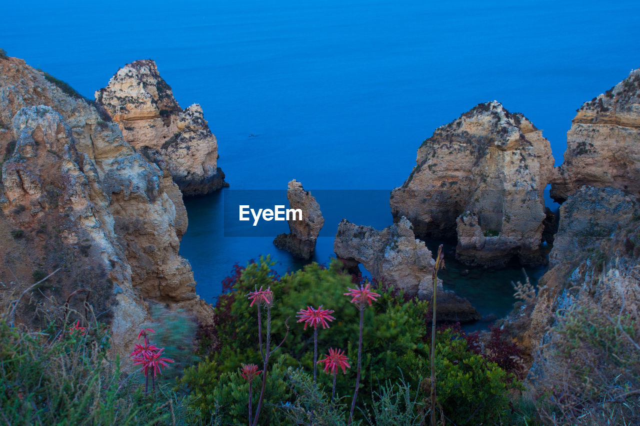 Rock formations by sea against blue sky