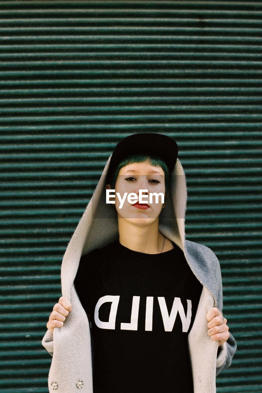 Portrait of punk woman standing against green shutter