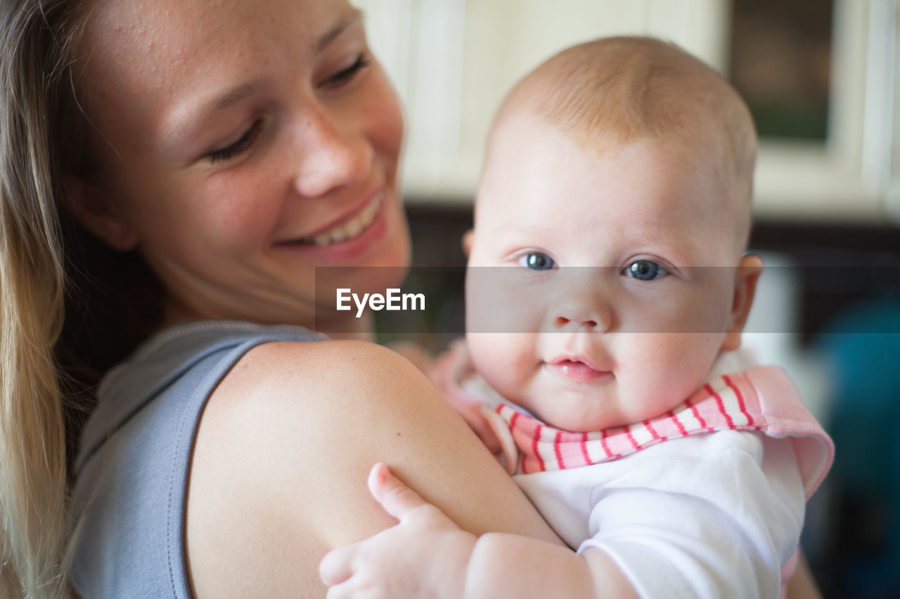 CLOSE-UP PORTRAIT OF HAPPY MOTHER AND BABY AT HOME