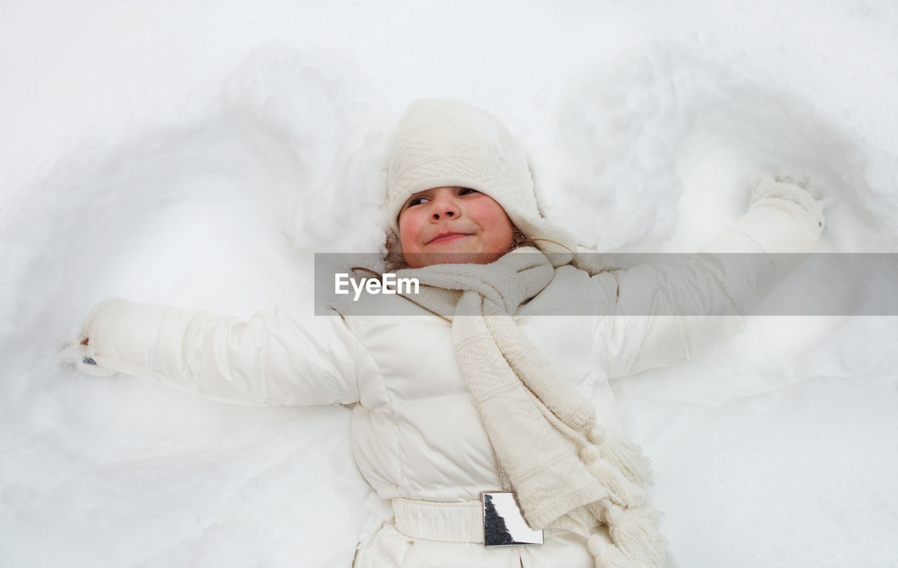 Full length of cute baby girl lying in snow