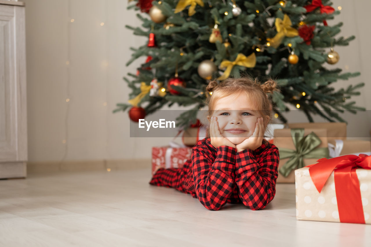 portrait of smiling girl decorating christmas tree on table