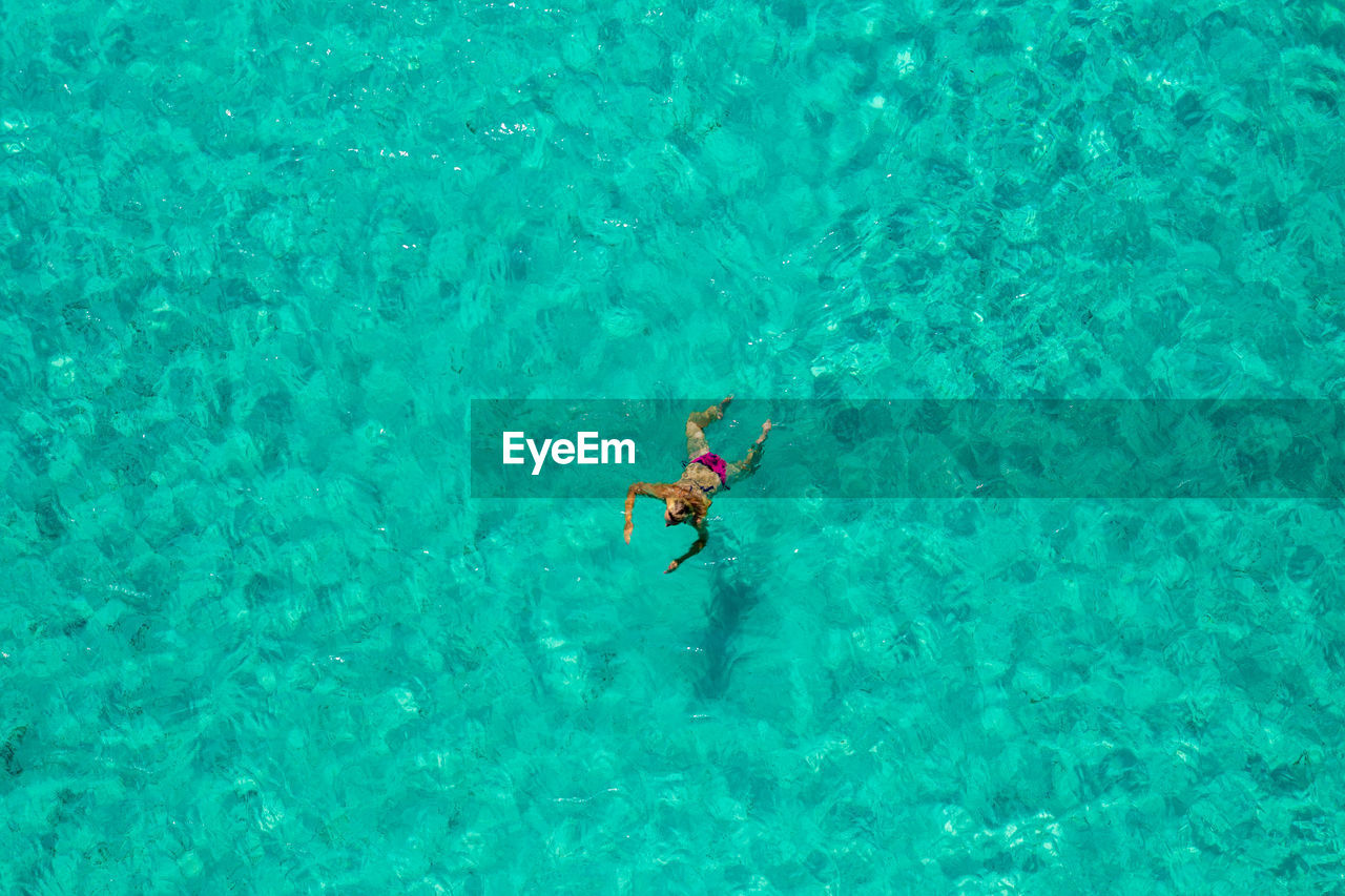 Aerial view of a girl floating in the turquoise sea of the sakarun beach, adriatic sea, croatia