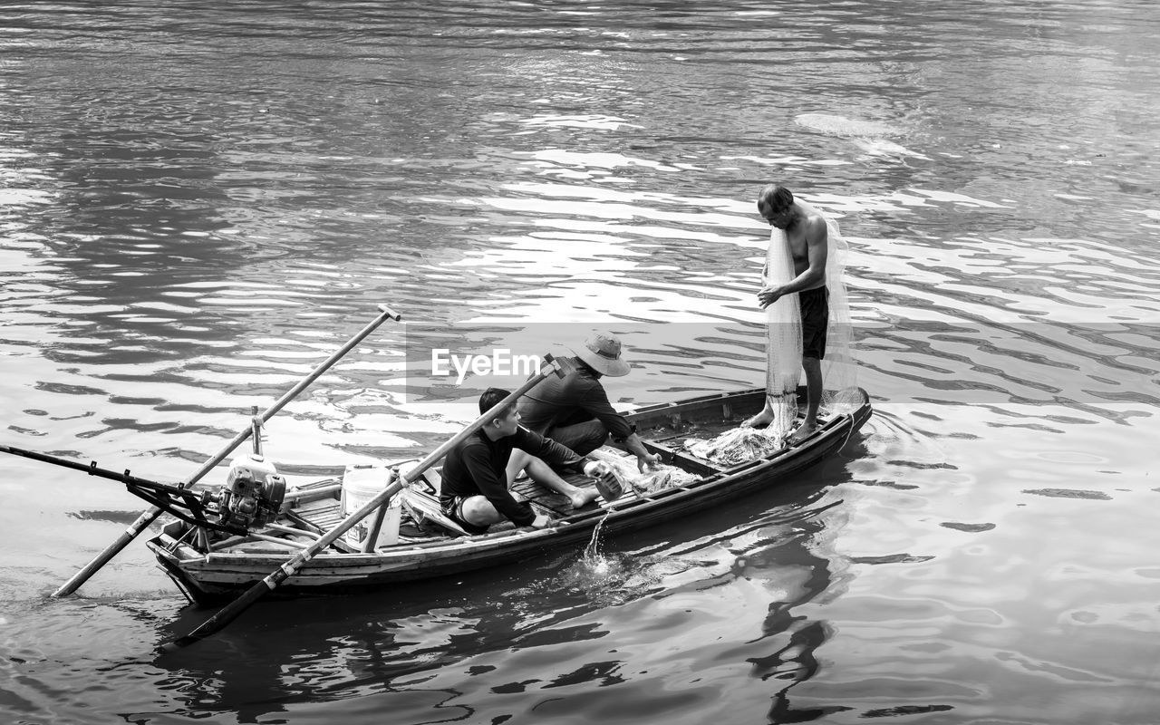 HIGH ANGLE VIEW OF MAN ROWING BOAT MOORED IN LAKE