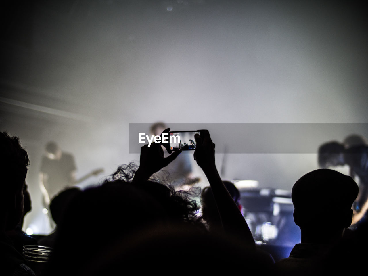 Cropped image of child photographing through smart phone at concert