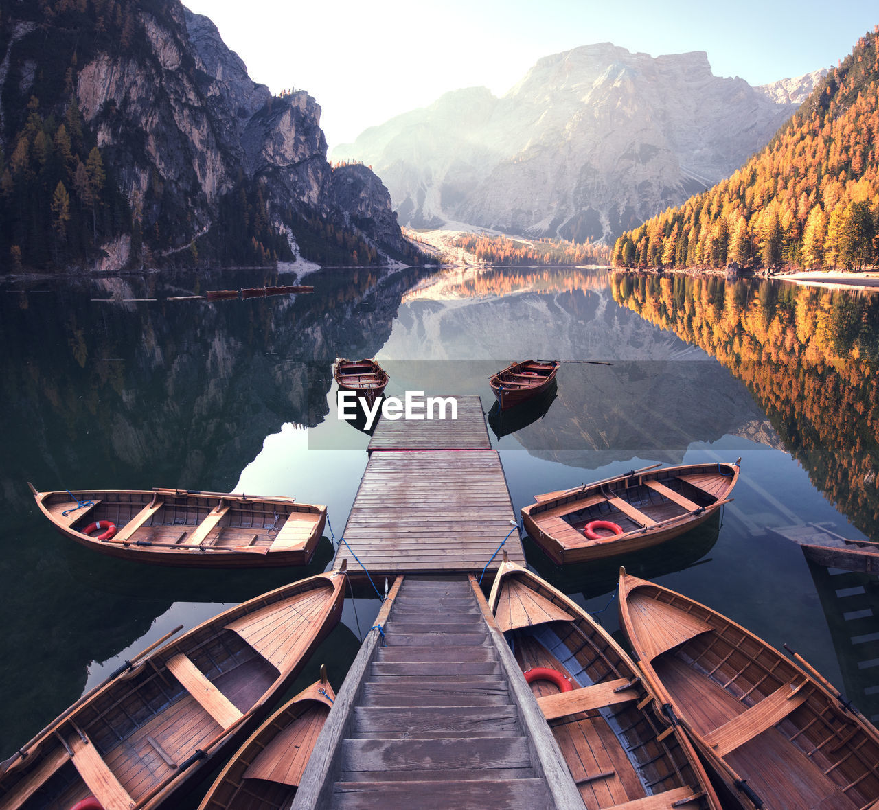 Boats moored around jetty in lake against mountains