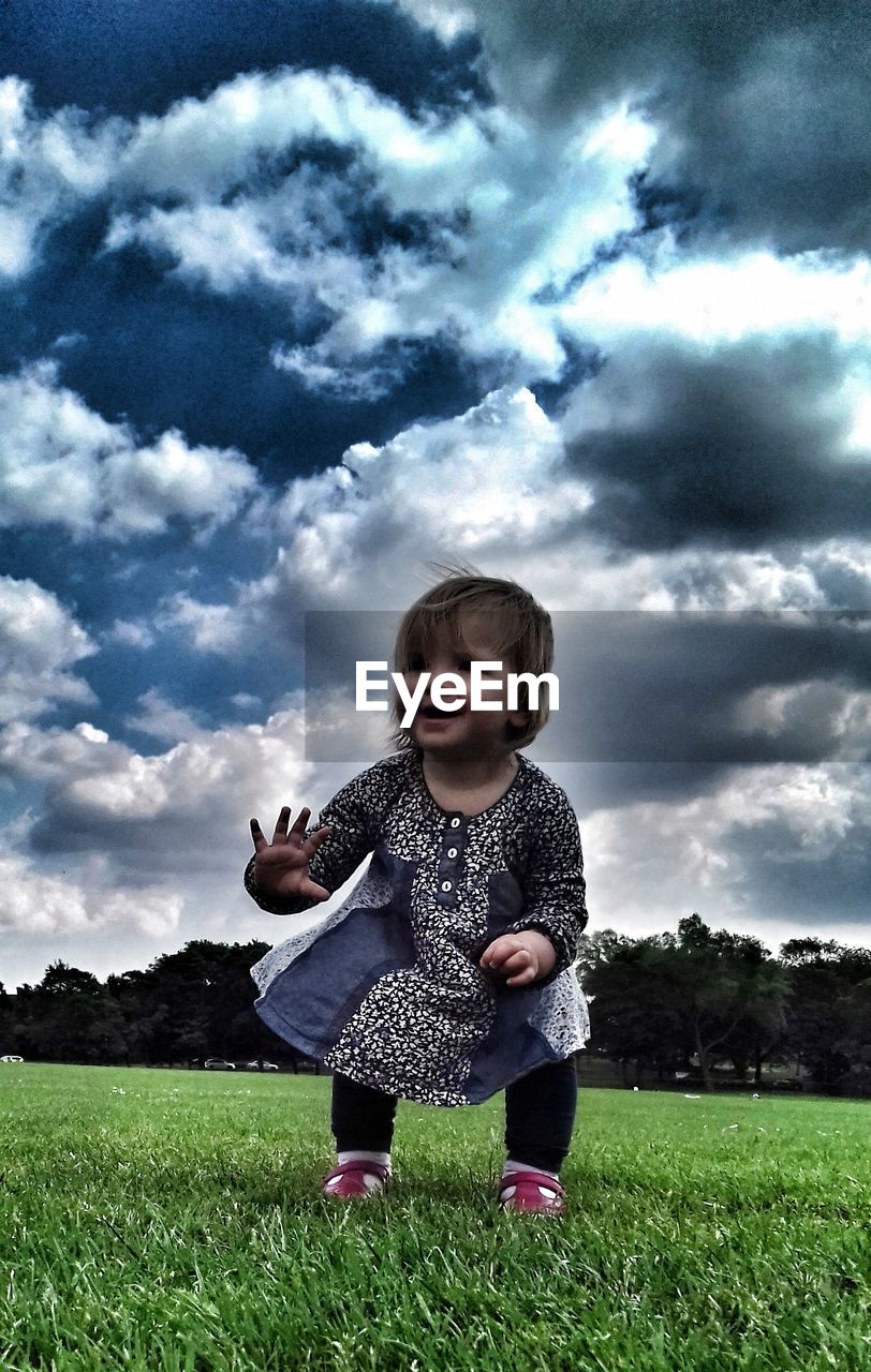 CUTE GIRL PLAYING ON FIELD AGAINST SKY