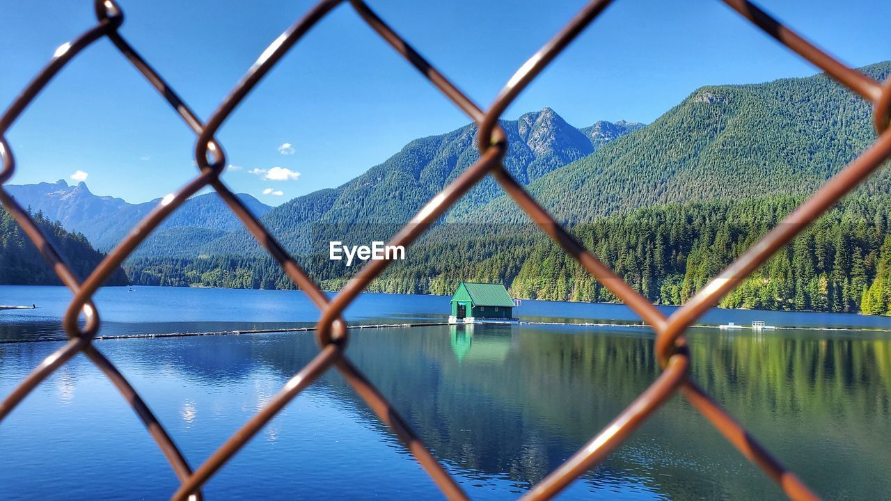 Lake seen through chainlink fence against sky