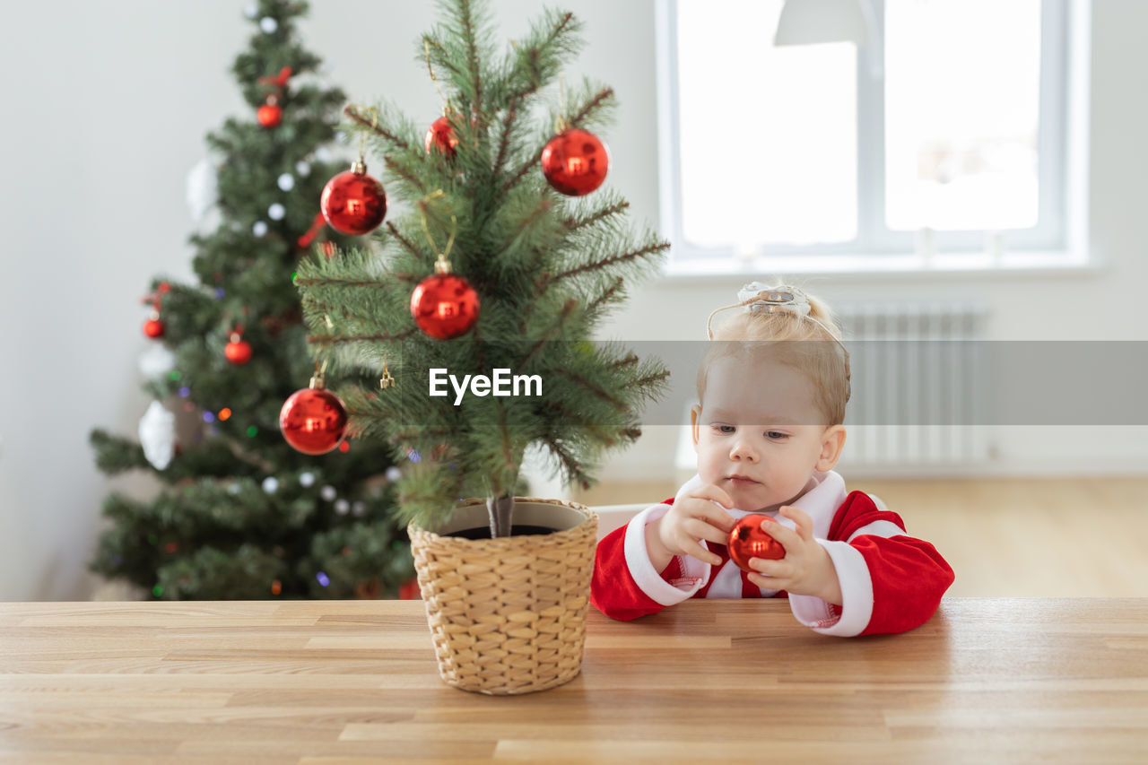 portrait of cute baby girl decorating christmas tree