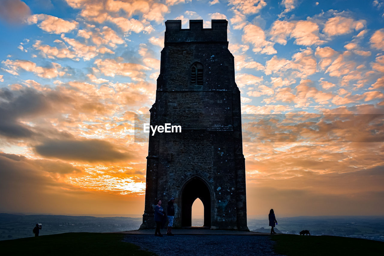 sky, tower, architecture, sunset, cloud, water, horizon, built structure, sea, dusk, nature, landmark, travel destinations, history, the past, evening, land, silhouette, travel, beauty in nature, lighthouse, building exterior, beach, scenics - nature, sunlight, tourism, outdoors, orange color, sun, building, dramatic sky, reflection, memorial, no people, ancient, environment, landscape, monument