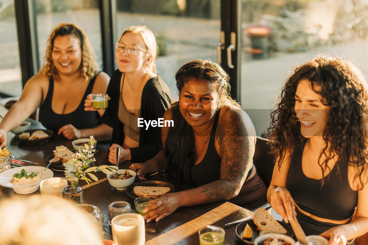 Happy female friends enjoying breakfast together at retreat center