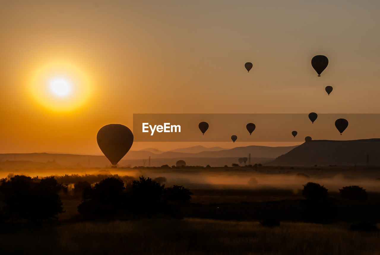 Silhouette hot air balloon flying against sky during sunset