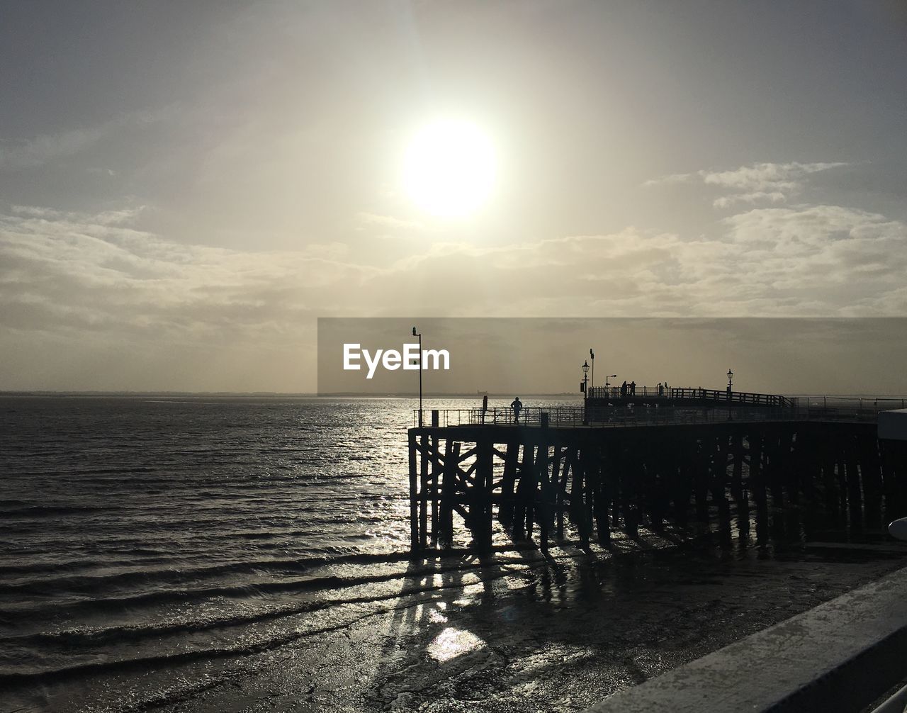 Silhouette of pier on sea at sunset