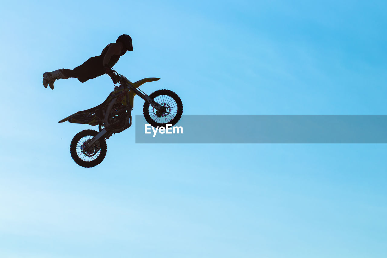 Low angle view of man jumping against sky