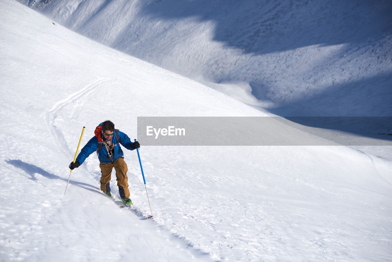 Man in blue jacket ski touring uphill