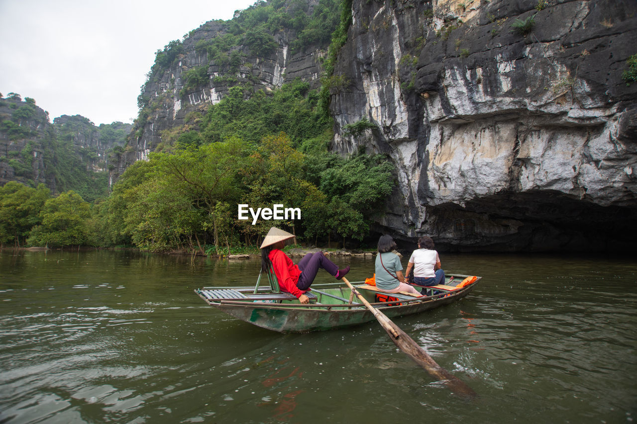 PEOPLE SITTING ON ROCK IN RIVER