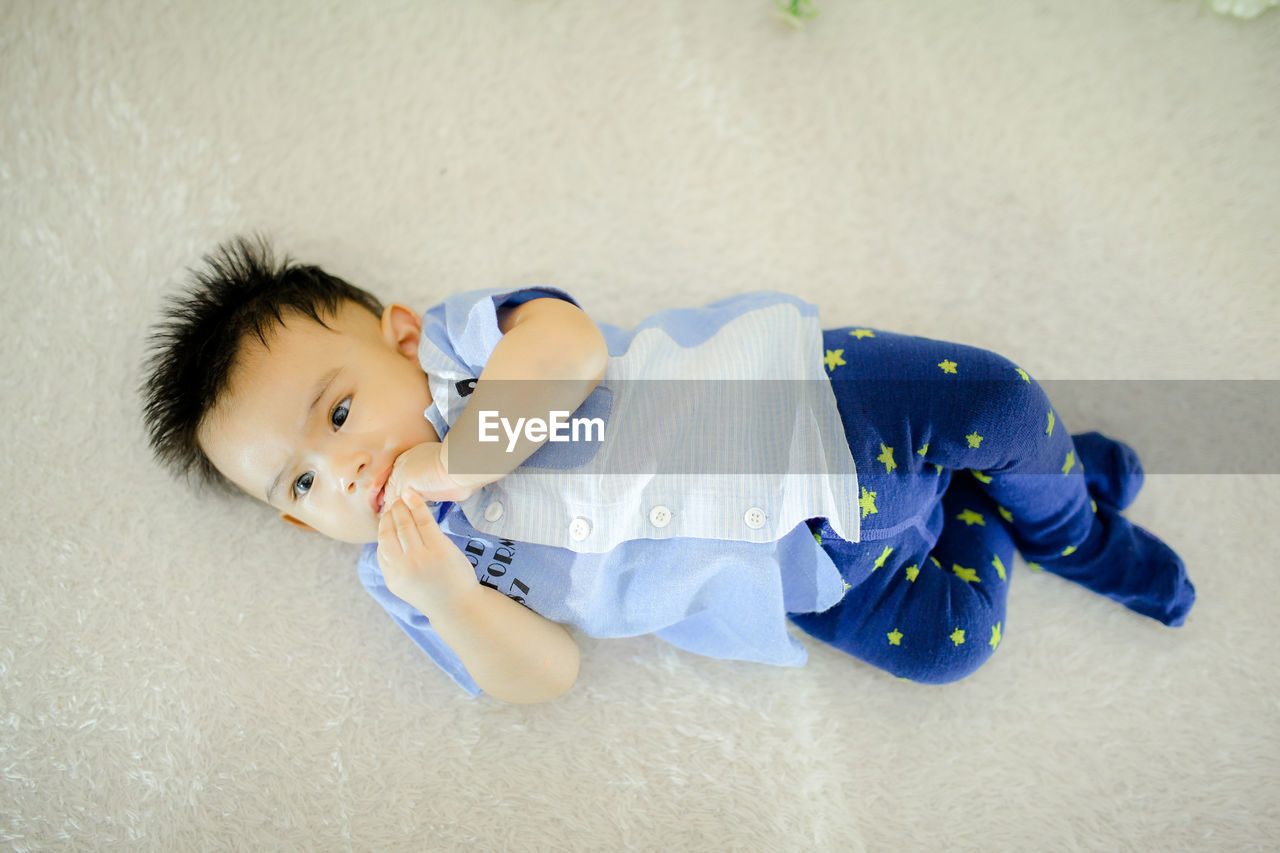 childhood, child, one person, blue, lying down, baby, toddler, high angle view, indoors, portrait, person, relaxation, innocence, cute, clothing, full length, men, looking at camera, white, black hair, toy, lying on back, emotion, smiling, human face