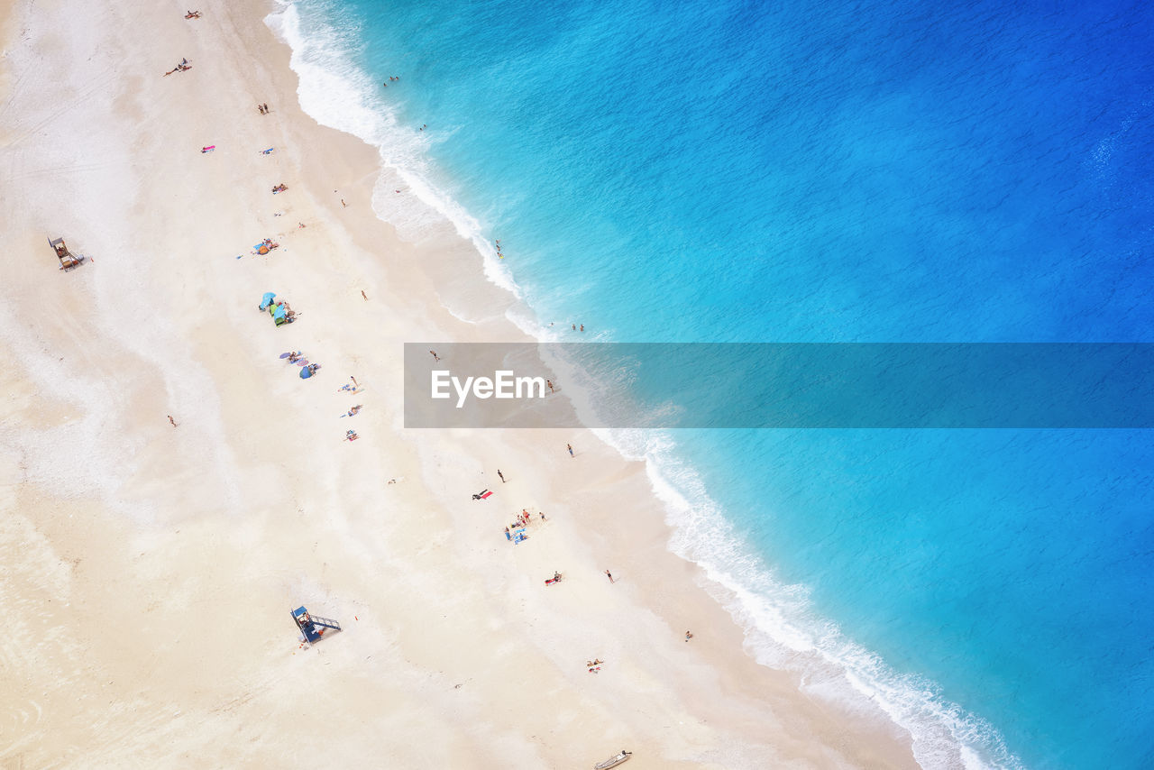 HIGH ANGLE VIEW OF PEOPLE ON BEACH AGAINST BLUE SKY