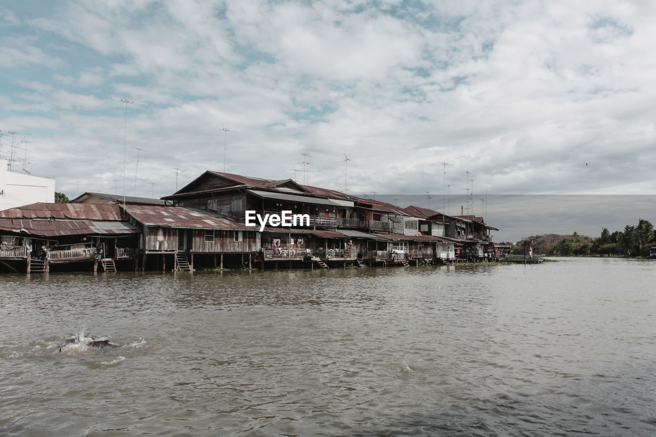 Houses by lake and buildings against sky