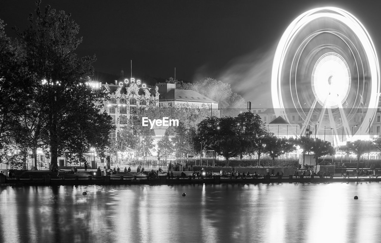 Illuminated city by river at night