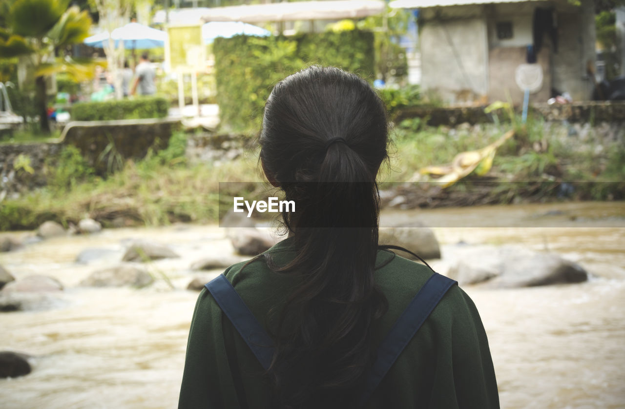 Rear view of woman standing by flowing water