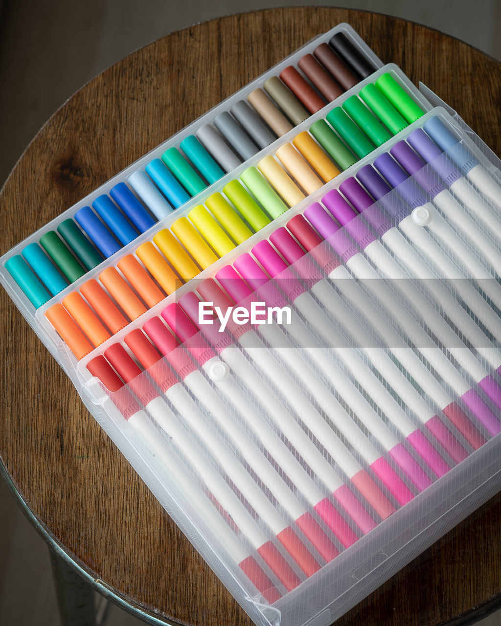 60 pieces of colorful markers in transparent plastic packaging on a wooden background.