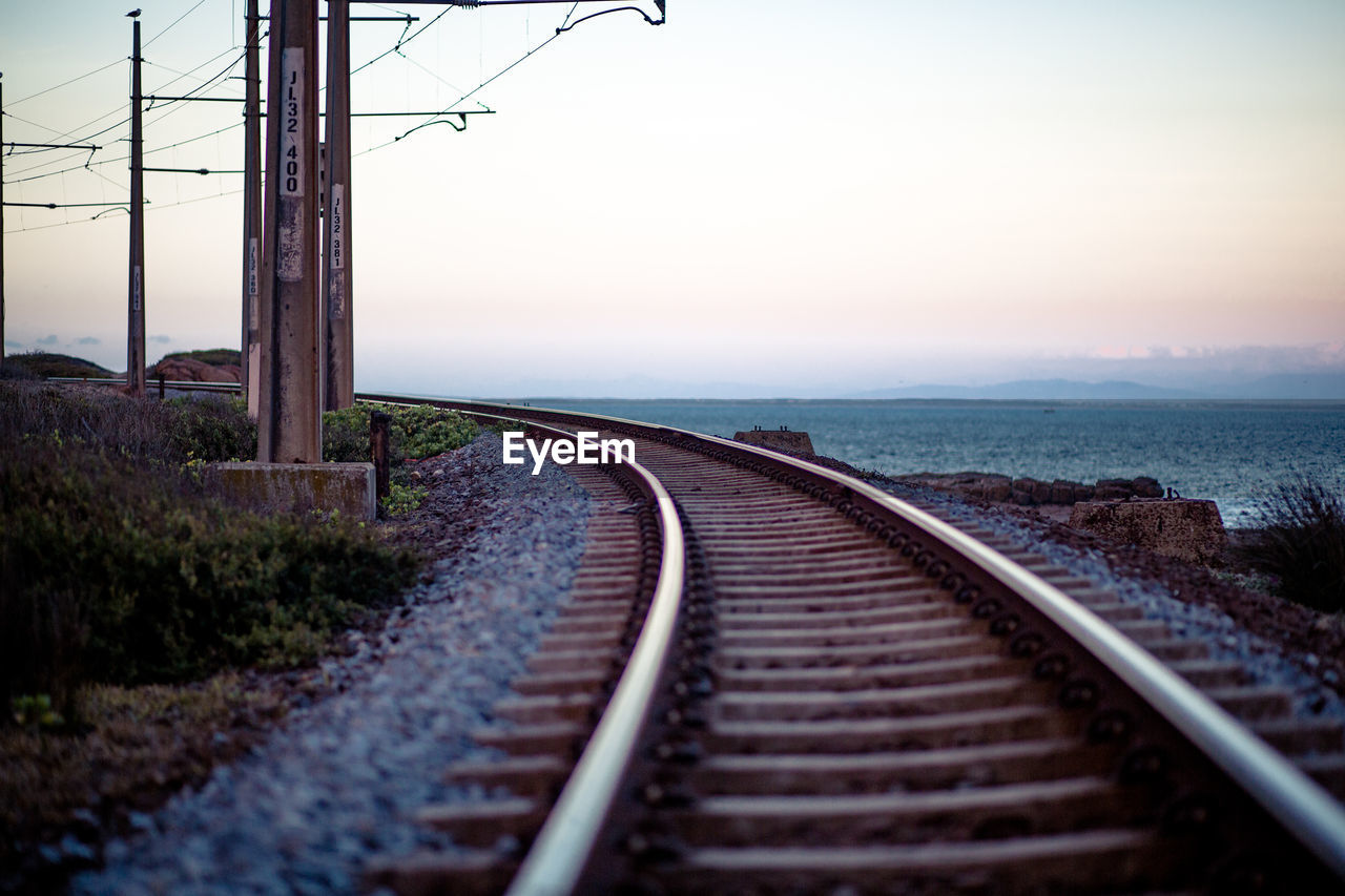 RAILROAD TRACK BY SEA AGAINST SKY