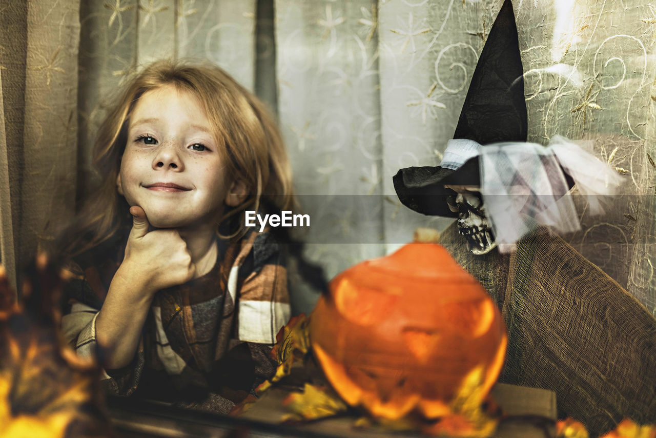 Portrait of young woman by window on the halloween decorations 